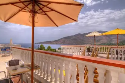 a balcony with an umbrella and a table and chairs at Seva' s Studios in Livadia