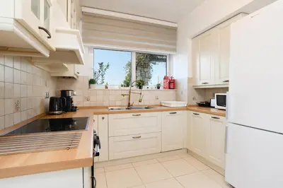 a kitchen with white cabinets and a sink and a window at Cathrin Beachfront Villa in Plimmiri