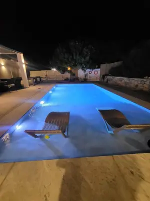 two chairs and a swimming pool at night at Cathrin Beachfront Villa in Plimmiri