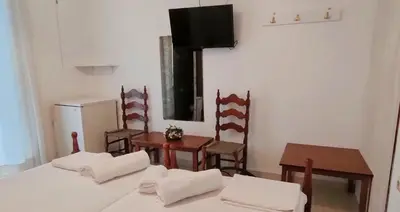 a room with two beds and chairs and a television at Cleopatra's House Apartments in Archangelos