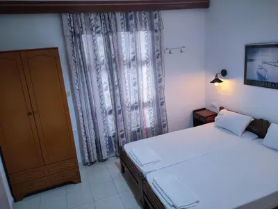 a bedroom with a white bed and a window at Cleopatra's House Apartments in Archangelos