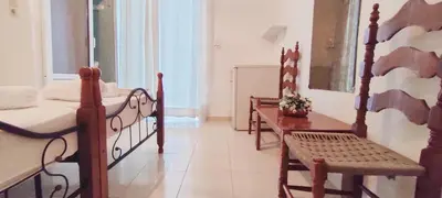 a bedroom with two beds and a table and a bench at Cleopatra's House Apartments in Archangelos