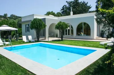 a swimming pool in the yard of a villa at Heliopetra Villa in Koskinou