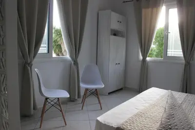 a bedroom with two chairs and a bed and two windows at Heliopetra Villa in Koskinou