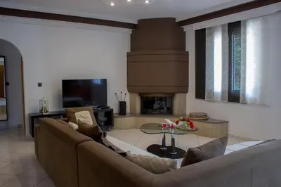 a living room with a couch and a fireplace at Heliopetra Villa in Koskinou
