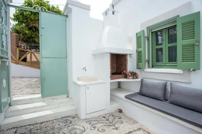 a house with green and white windows and a bench at Marouli Traditional Villa in Koskinou
