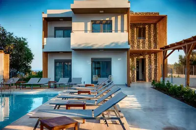 a resort with a swimming pool with lounge chairs at Kipos Suites & Apartments in Gennadi