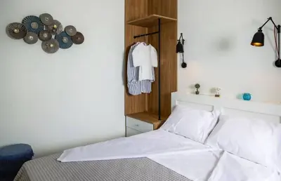 a bedroom with a bed with white sheets and a shelf at Kipos Suites & Apartments in Gennadi