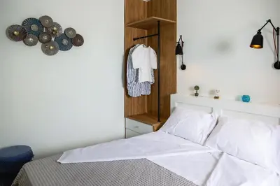 a bedroom with a bed with white sheets and wooden walls at Kipos Suites & Apartments in Gennadi
