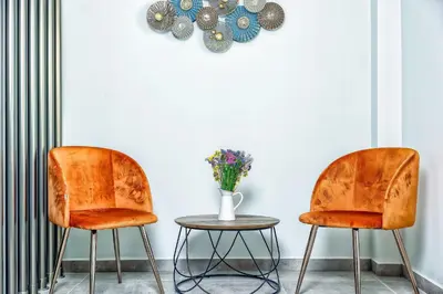 two orange chairs and a table with a vase of flowers at Kipos Suites & Apartments in Gennadi
