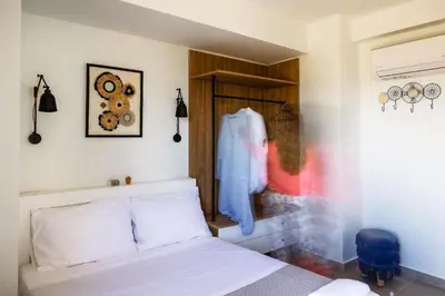 a bedroom with a white bed and a wooden cabinet at Kipos Suites & Apartments in Gennadi