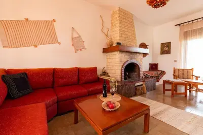 a living room with a red couch and a fireplace at Alonia Summerhouse in Fanes in Phanaes