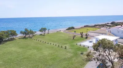 an aerial view of a field of grass next to the ocean at Celini beach house in Kiotari