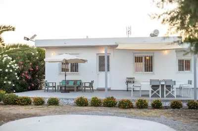 a white house with a table and an umbrella at Celini beach house in Kiotari
