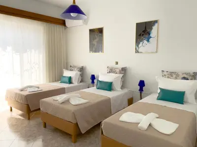 a room with three beds with towels on them at NJ Apartments: The Island Edition in Rhodes Town