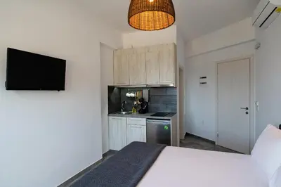 a bedroom with a white bed and a kitchen at Aethrèa Apartments in Haraki