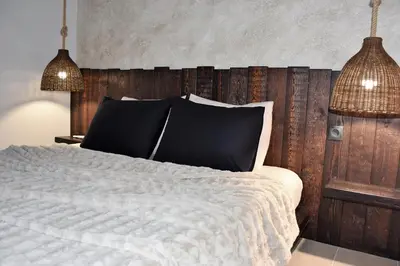 a bedroom with a white bed with black pillows at Aethrèa Apartments in Haraki