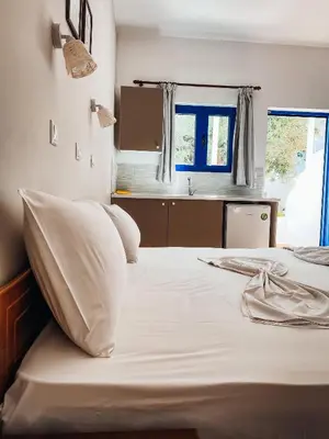 a bedroom with a bed with white sheets and a window at Lindos Athena in Líndos