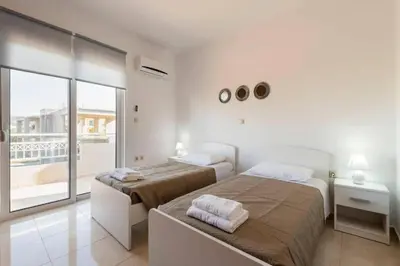 a white bedroom with two beds and a balcony at Angels Villa in Kremasti