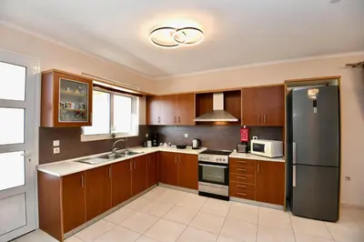 a kitchen with wooden cabinets and a stainless steel refrigerator at Angels Villa in Kremasti
