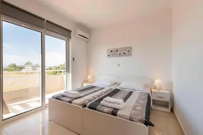 a white bedroom with a bed and a large window at Angels Villa in Kremasti