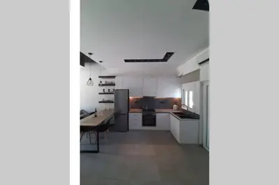 a kitchen with white cabinets and a table in it at Luxury 1 bedroom apartment in Ialysos in Ialyssos