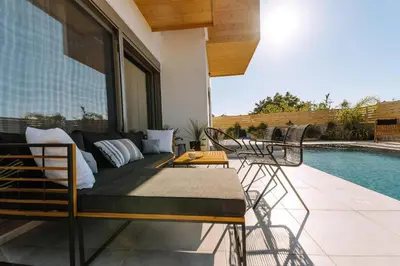 a patio with a couch and chairs next to a pool at Brillante Villa in Ialyssos