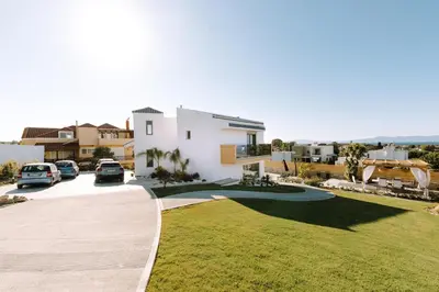 a white house with cars parked in a driveway at Brillante Villa in Ialyssos