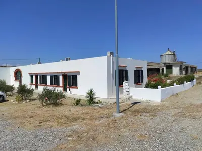 a white building with a water tower in the background at San Marco Guesthouse in Kattavía