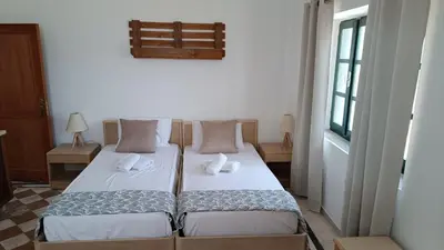 two twin beds in a room with a window at San Marco Guesthouse in Kattavía