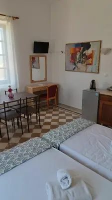 a room with two beds and a table and a desk at San Marco Guesthouse in Kattavía