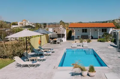 a swimming pool with lounge chairs and a house at Reni Garden House in Afantou