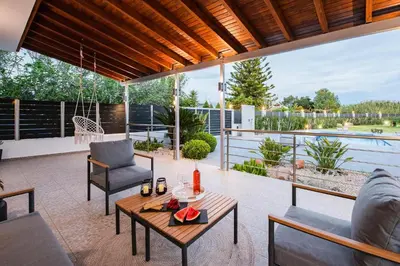 a patio with a table and chairs and a pool at Reni Garden House in Afantou