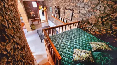 a bedroom with a green bed in a stone wall at Yiannis Village house in Asklipiḯon