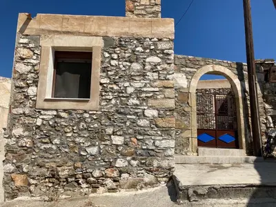 a stone building with a window and a door at Yiannis Village house in Asklipiḯon