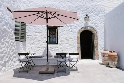 a table with chairs and a pink umbrella in front of a building at 1919's House in Asklipiḯon