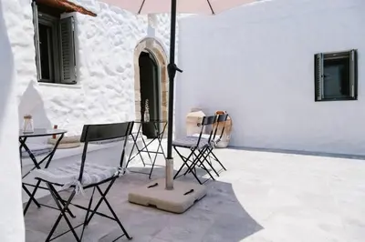 a group of chairs and an umbrella on a patio at 1919's House in Asklipiḯon