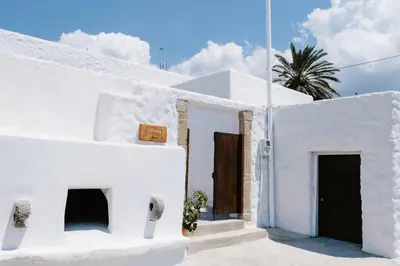 a white building with two doors and a palm tree at 1919's House in Asklipiḯon