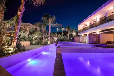 an exterior of a house at night with purple lights at Vanik Suites in Faliraki