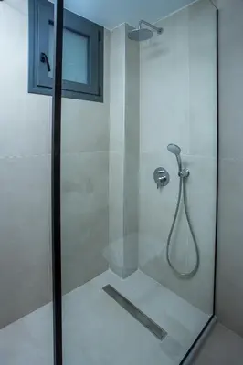 a shower with a glass door with a shower head at Vanik Suites in Faliraki