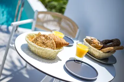a table with two baskets of bread and two glasses of orange juice at Vanik Suites in Faliraki