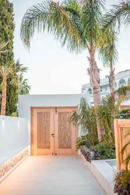 a wooden garage with a palm tree in front of it at Vanik Suites in Faliraki