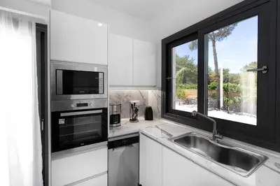 a kitchen with a sink and a microwave and a window at DASÝLIO - earthy living homes in Triánta