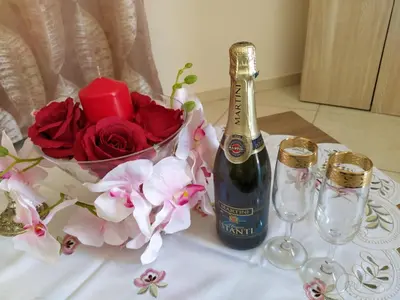 a bottle of champagne and a vase of flowers on a table at Vila Elion Myloi in Symi