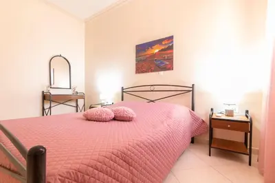 a bedroom with a pink bed with two pillows on it at Vila Elion Myloi in Symi
