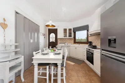 a white kitchen with a white table and chairs at Evi's Afandou Suite in Afantou