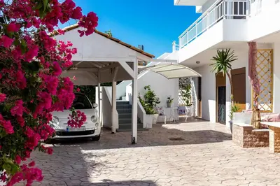 a white house with a car parked in a driveway at Evi's Afandou Suite in Afantou