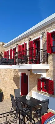 a table and chairs in front of a building with red shutters at VILLA ELENA in Halki