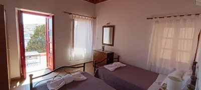 a bedroom with two beds and a large window at VILLA ELENA in Halki
