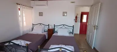 two beds in a room with a red door at VILLA ELENA in Halki